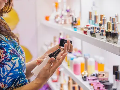 Woman with cosmetics in her hand in front of shelves with various cosmetics